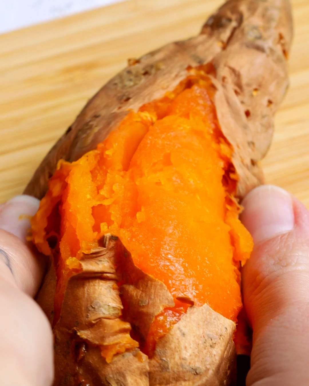 Peeling skin off a roasted sweet potato.