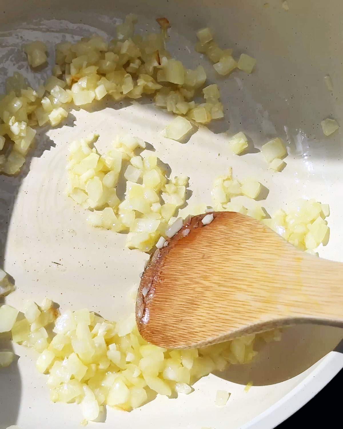 Stirring onion and garlic in a skillet.