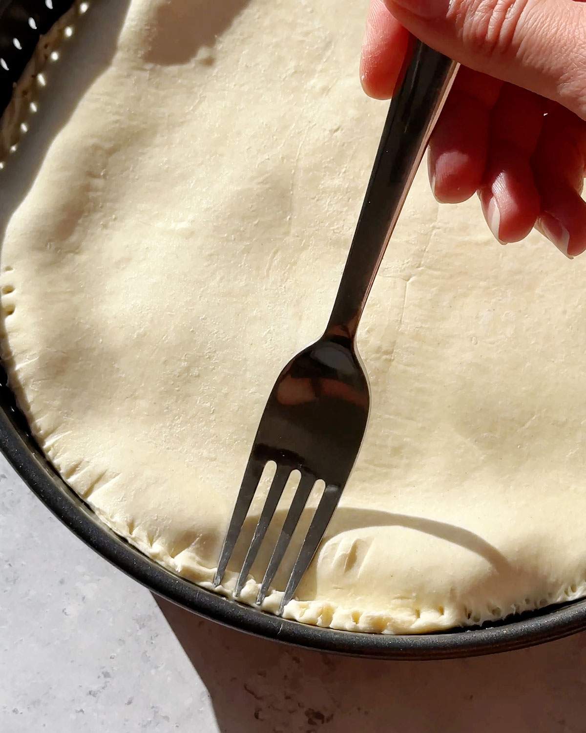 Sealing the edges of the pie pastry with a fork.