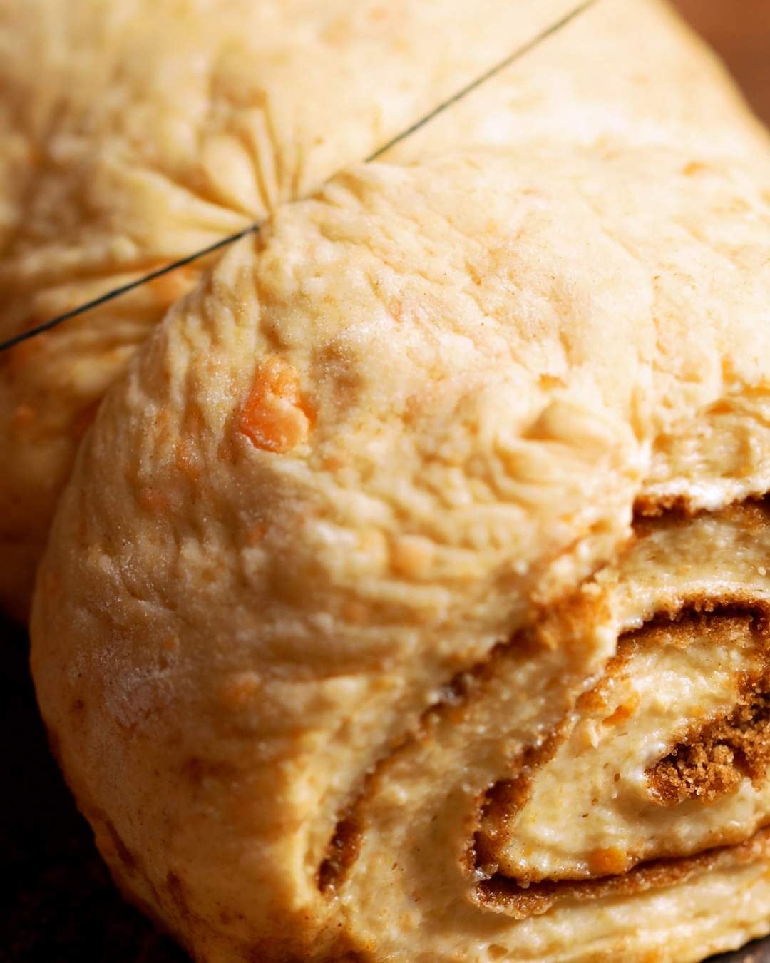 Slicing rolled cinnamon roll dough with dental floss.
