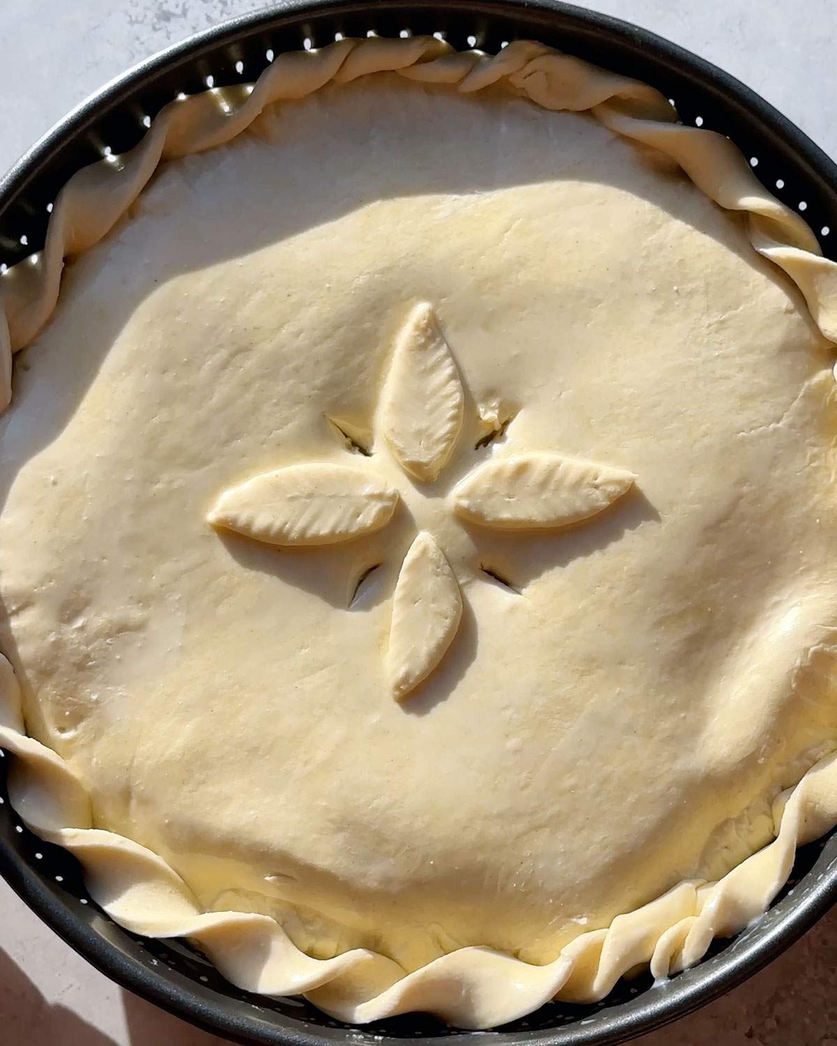 Decorated pot pie with slits cut into the top before baking.
