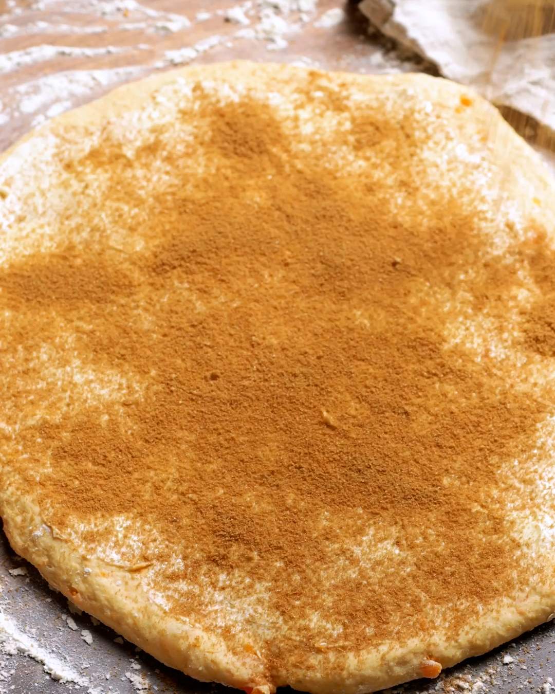 Cinnamon sugar sprinkled onto cinnamon roll dough.