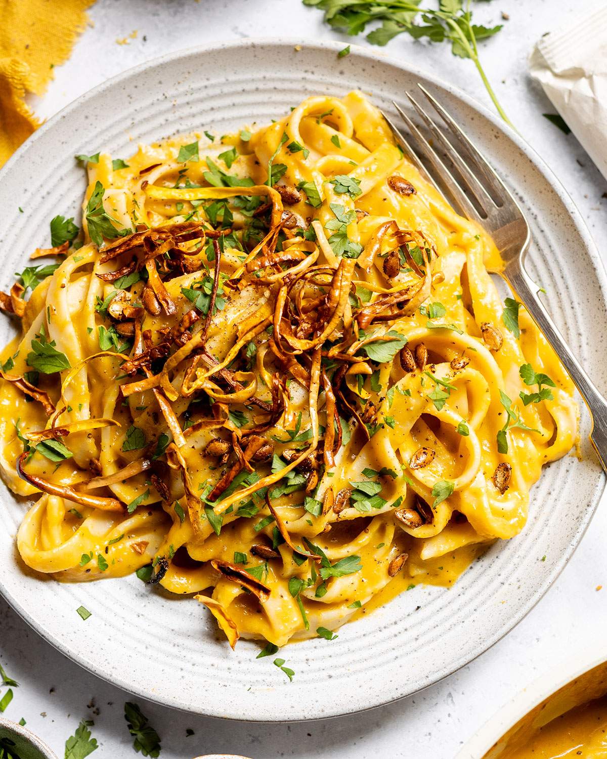 Creamy butternut squash tagliatelle on a plate with crispy squash on top and a fork on the side.