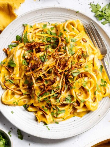 A plate of creamy butternut squash pasta with crispy squash on top.