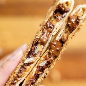 Two smores crunchwraps cut open up close showing melted chocolate and marshmallows inside.