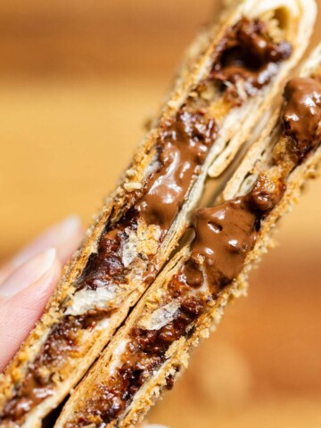 Two smores crunchwraps cut open up close showing melted chocolate and marshmallows inside.