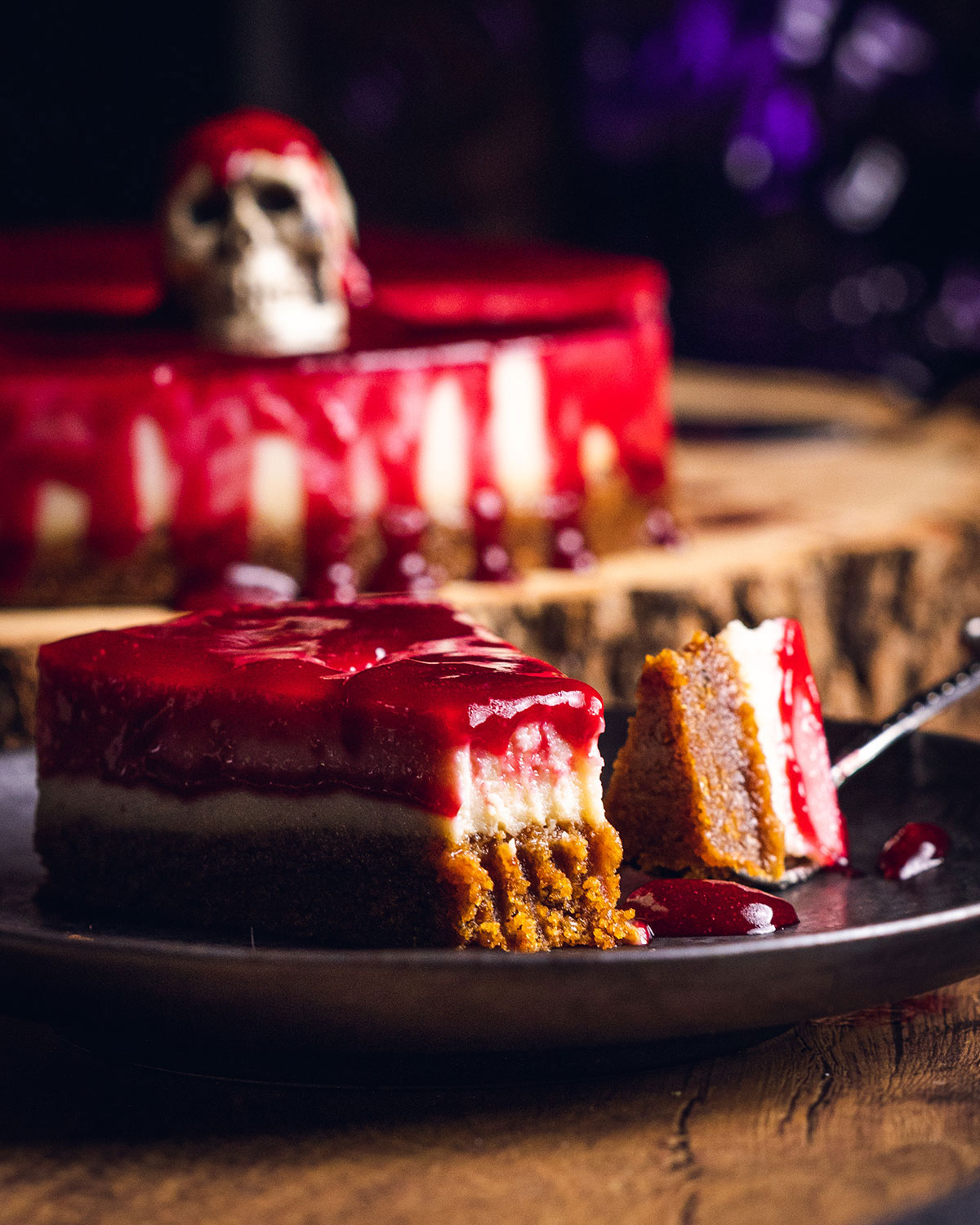 A slice of lemon raspberry cheesecake on a serving platter, decorated for halloween.