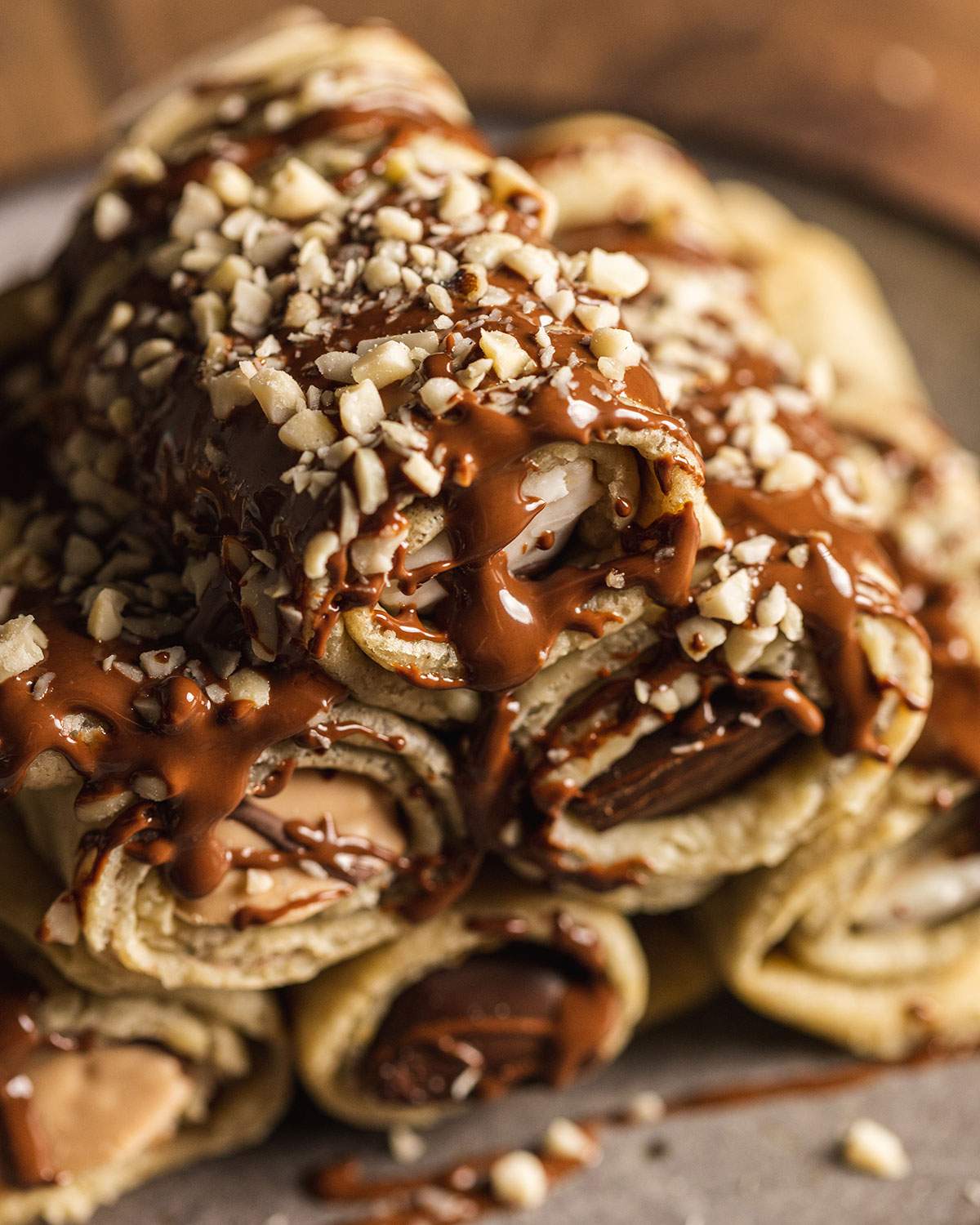 Stacked stuffed crepe rolls with chocolate on top.