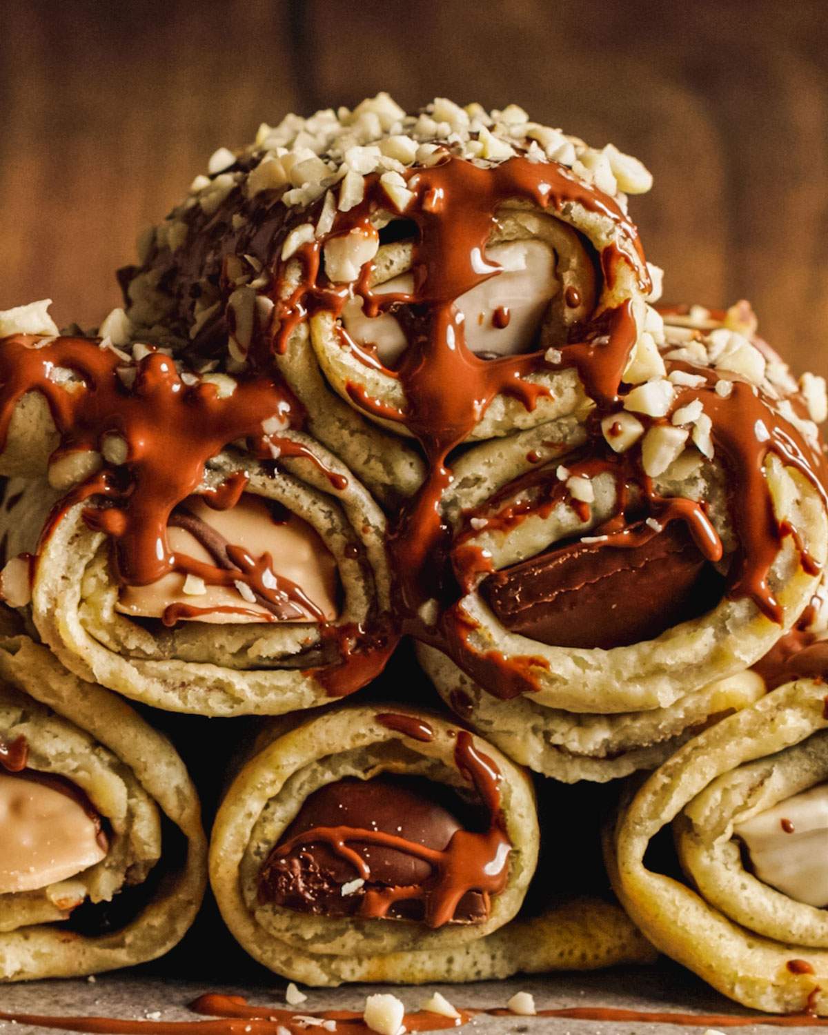 Stacked stuffed vegan crepe rolls with chocolate drizzle on top.