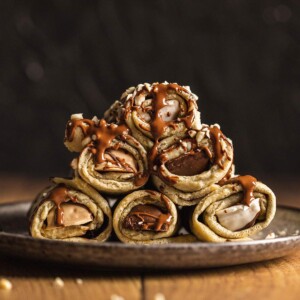 Stacked stuffed crepe rolls on a plate.