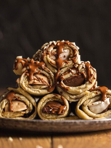 Stacked stuffed crepe rolls on a plate.