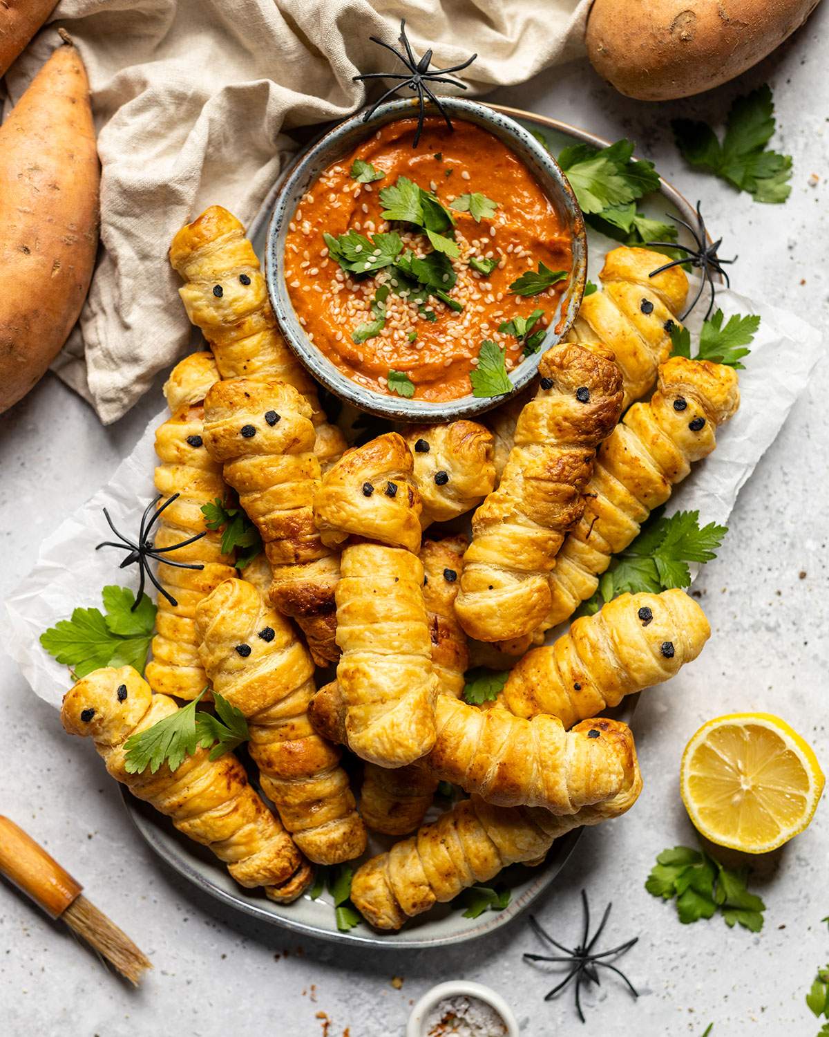 Pastry wrapped sweet potato fingers on a platter with a dip.