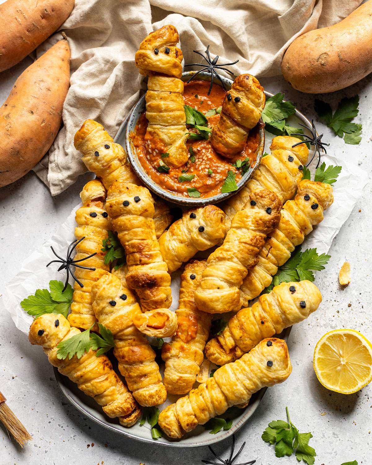 Pastry wrapped sweet potato fingers on a platter with a dip.