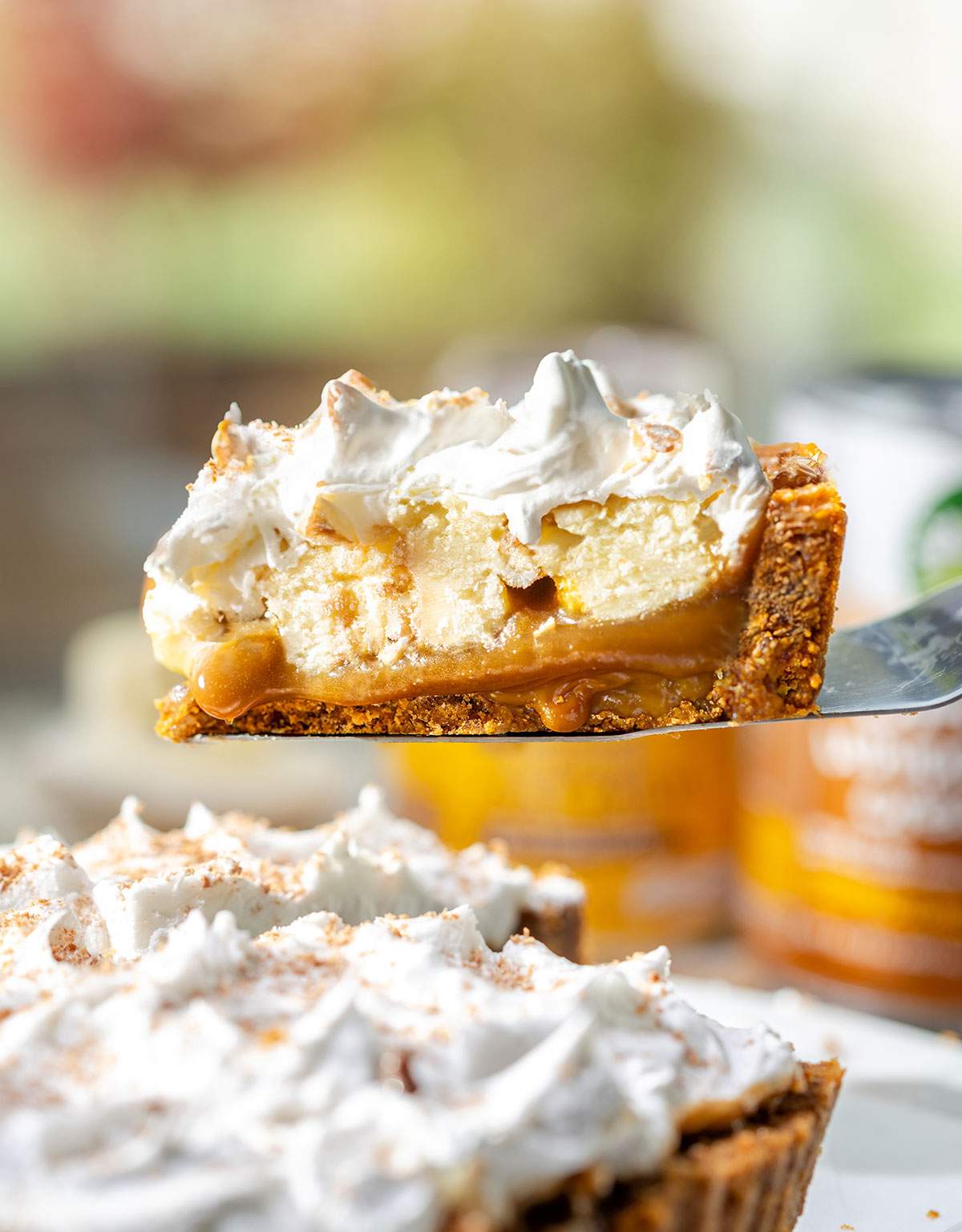 A slice of vegan banoffee pie lifted on a cake spatula with all layers of the pie shown.