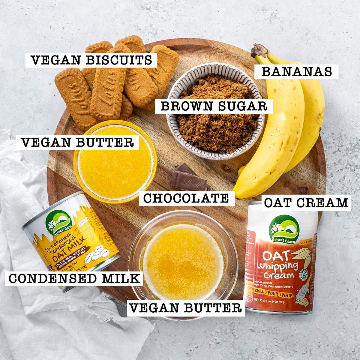 Ingredients for vegan banoffee pie on a wooden board with labels.