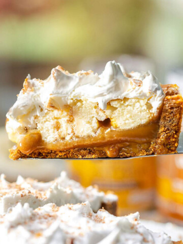 A slice of vegan banoffee pie lifted from the pie with layers of biscuit base, toffee sauce, banana slices and whipped vegan cream visible.