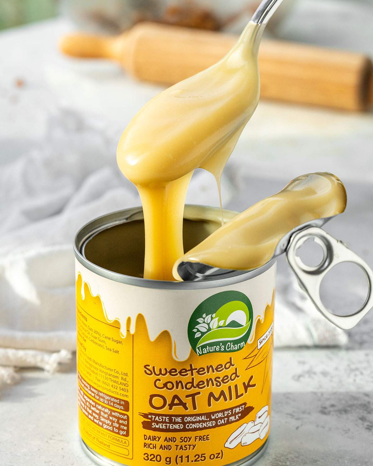 A spoon lifting smooth vegan condensed milk out of a can.