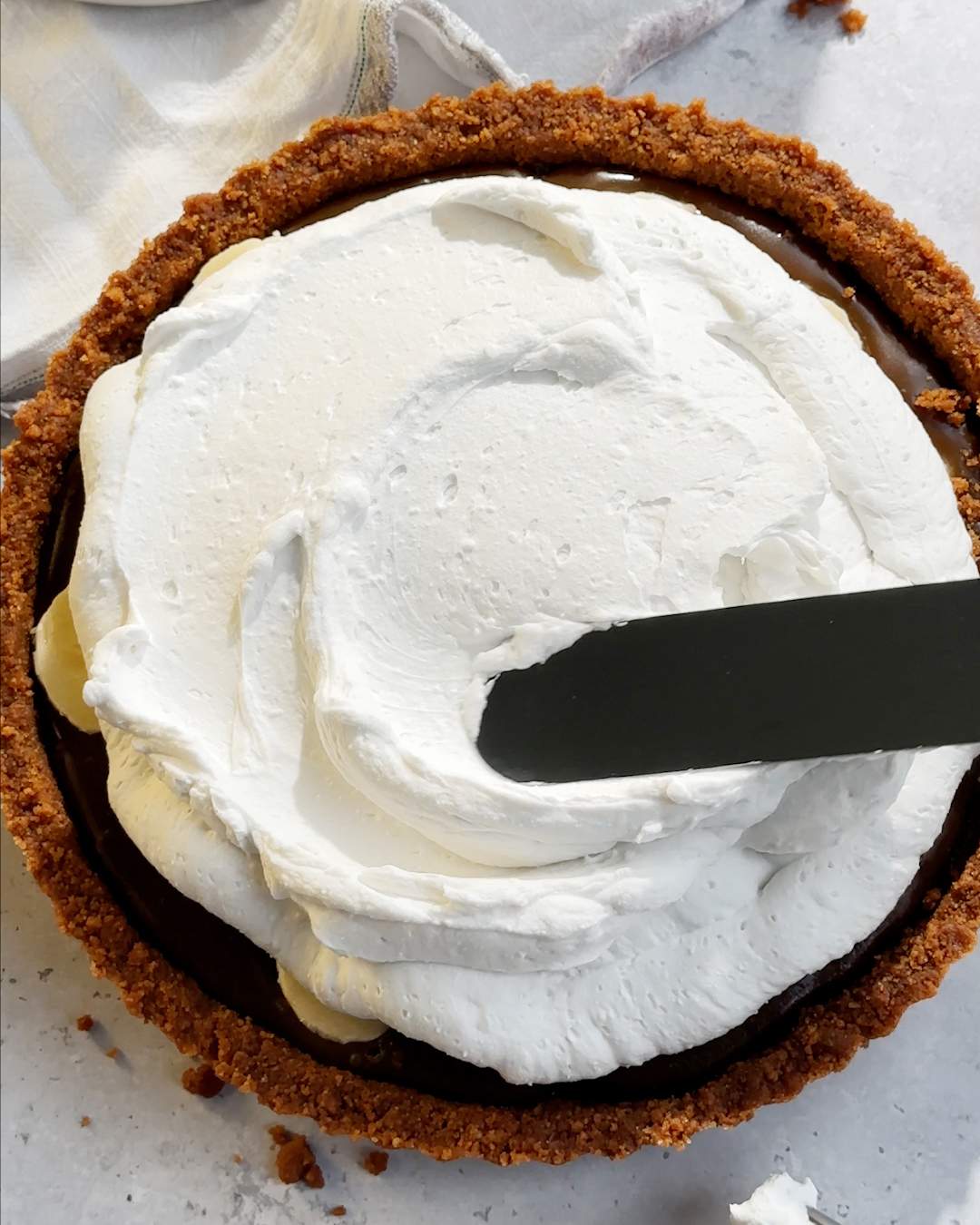 Spreading whipped cream onto pie with a pallet knife.