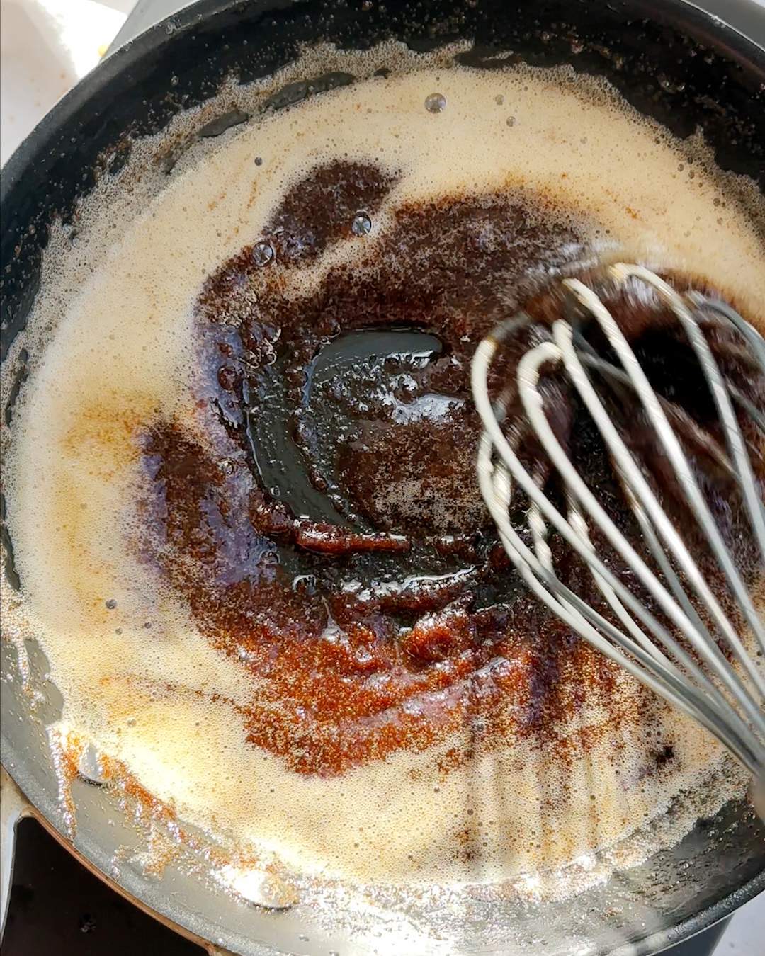 Whisking melted butter and sugar in a pan.