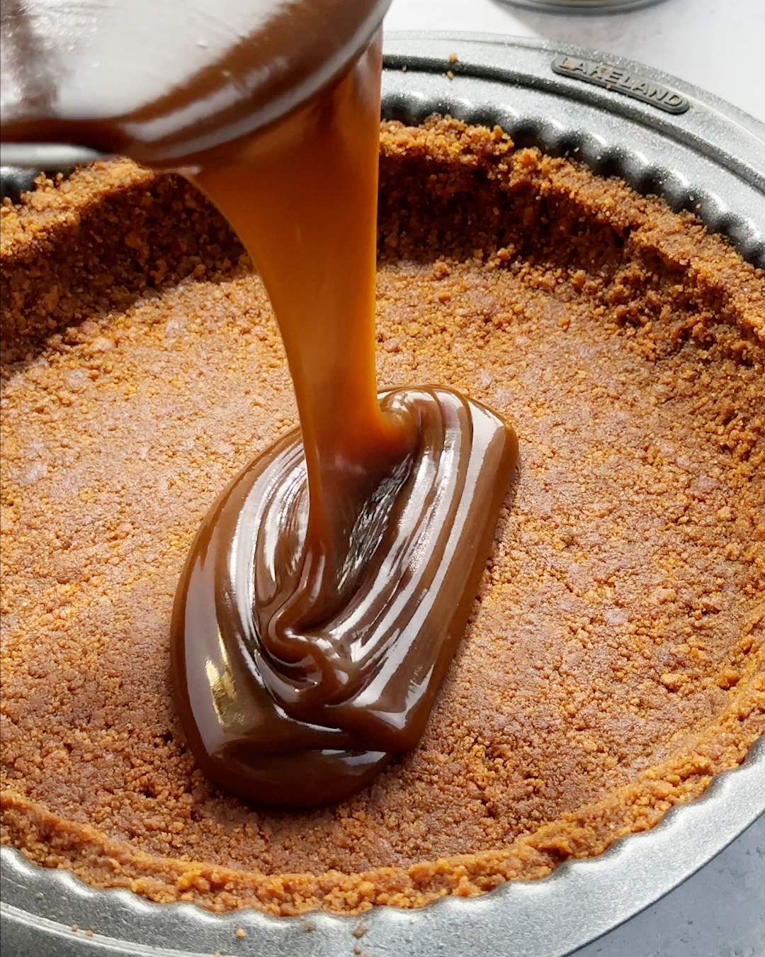 Pouring toffee sauce onto pie crust.