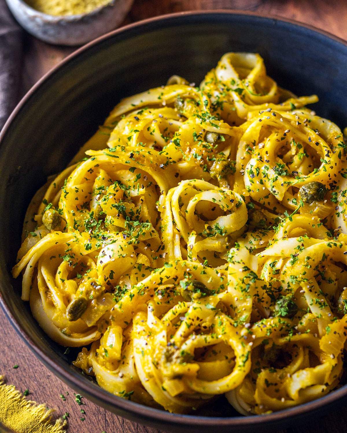 Creamy pumpkin linguine topped with herbs in a dinner bowl.