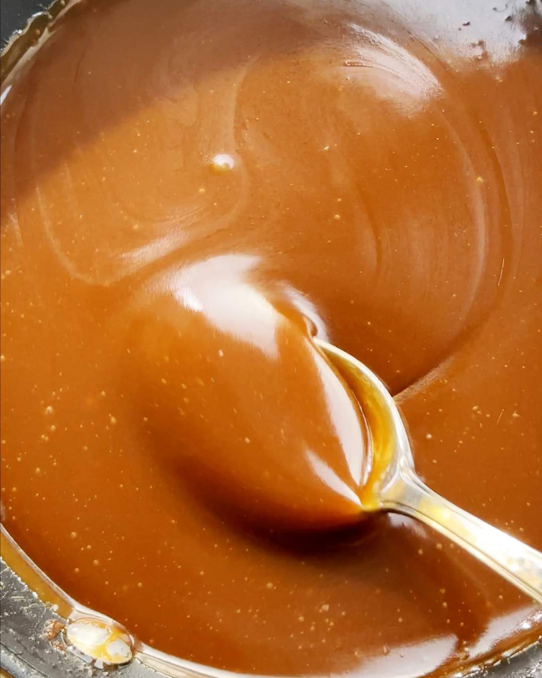 Stirring thick toffee sauce with a spoon.