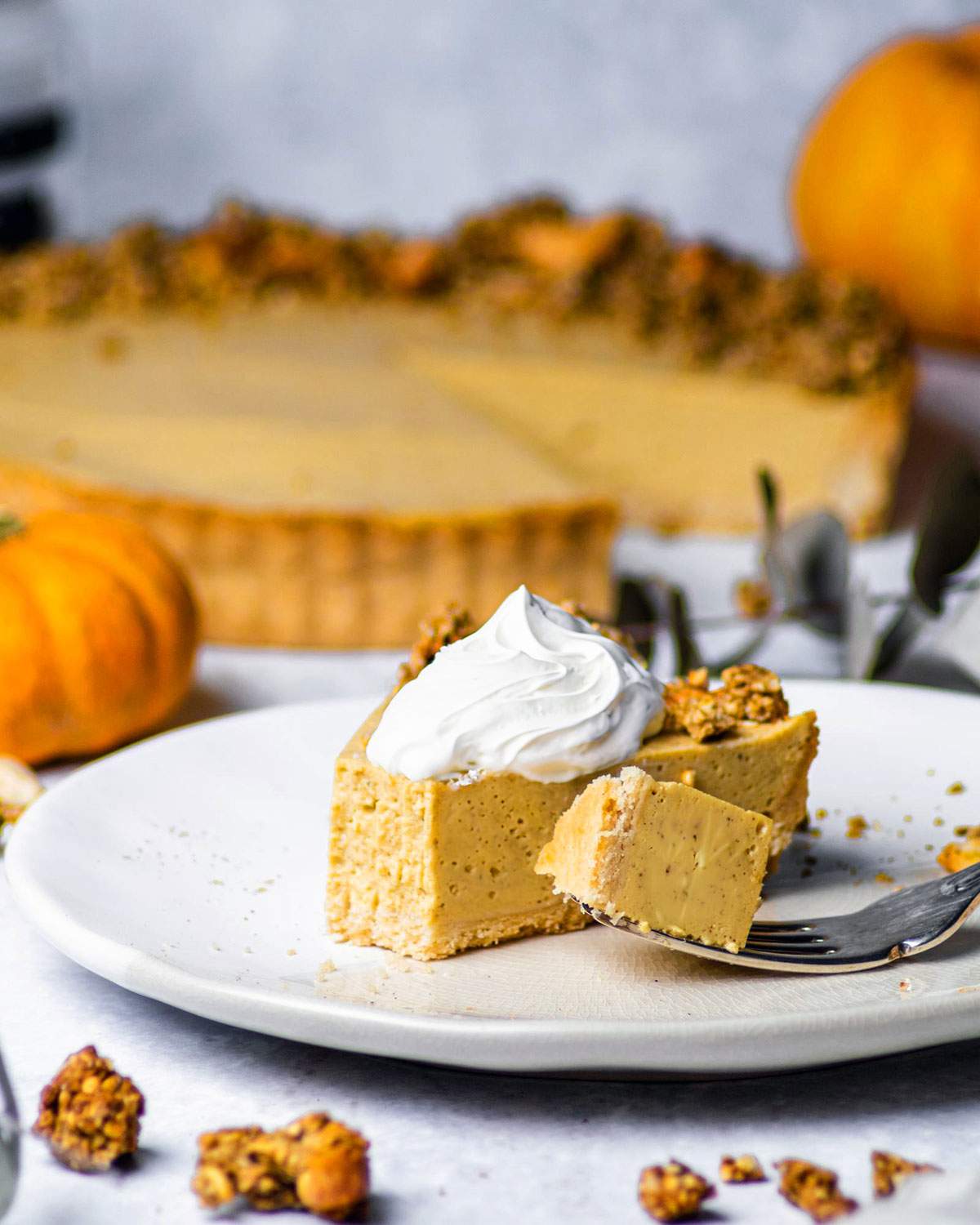 A slice of pumpkin cheesecake with whipped cream and a fork next to it.