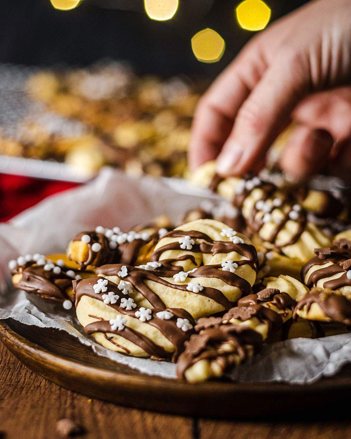 Festive vegan spritz cookies with chocolate coating on a serving platter.