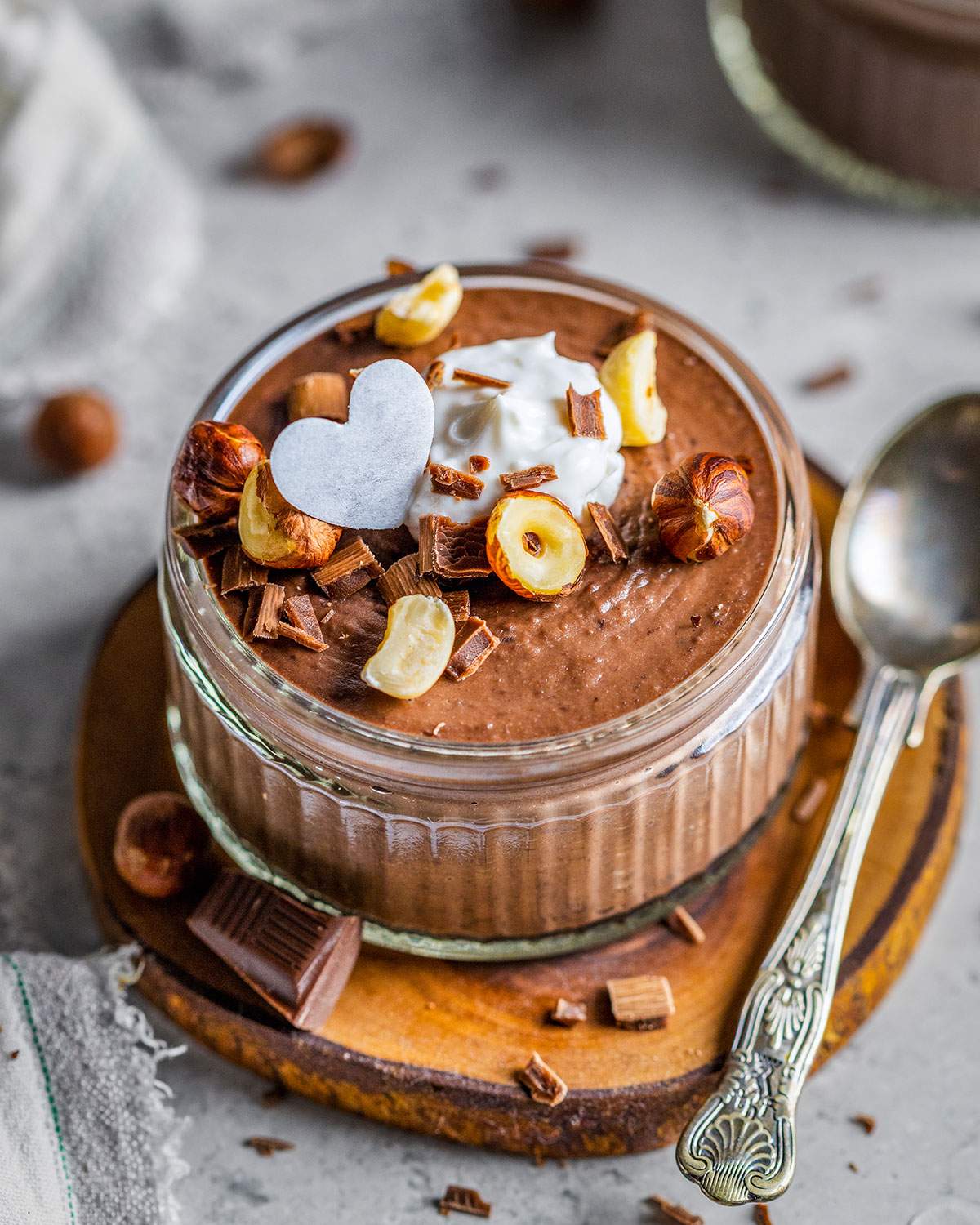 Creamy chocolate mousse in a ramekin with hazelnuts on top.
