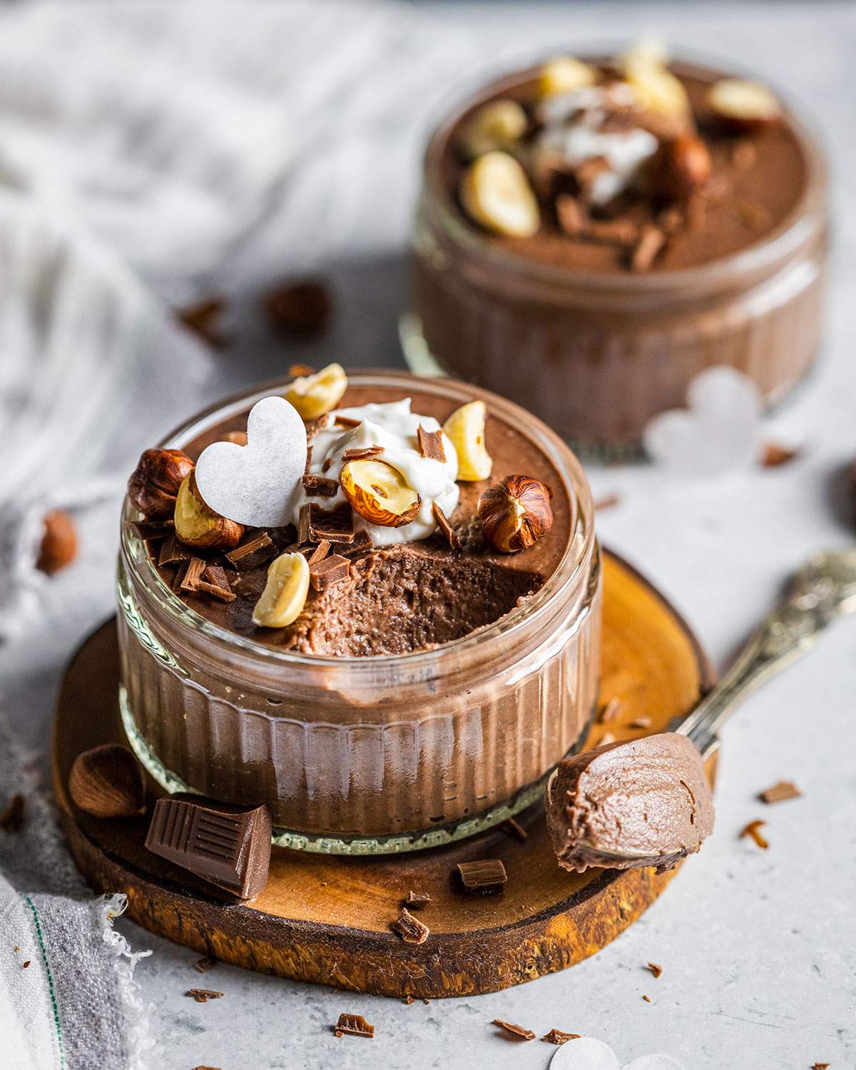 Creamy chocolate mousse in a ramekin with a spoon next to it.