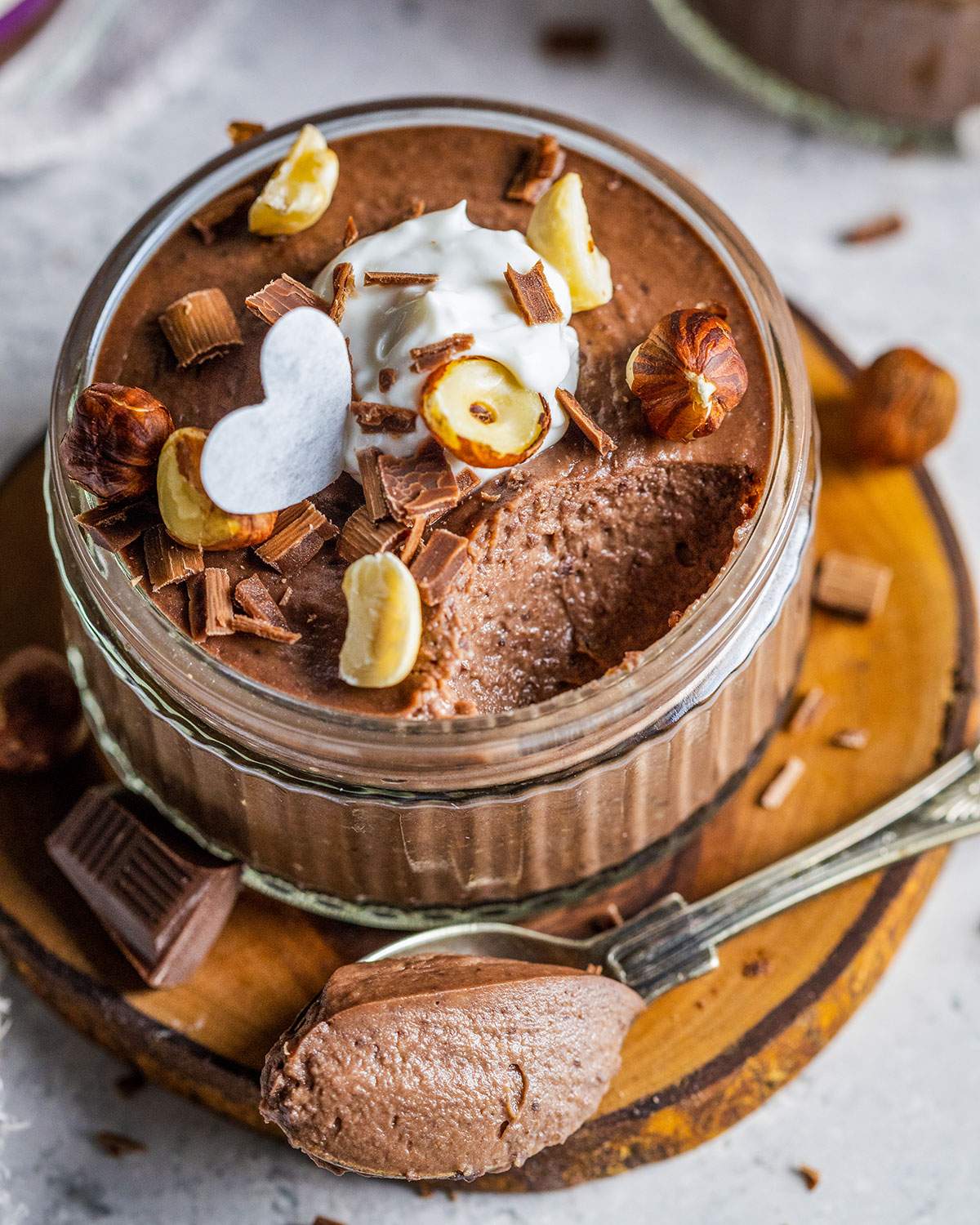 Creamy chocolate mousse in a ramekin with a spoon.