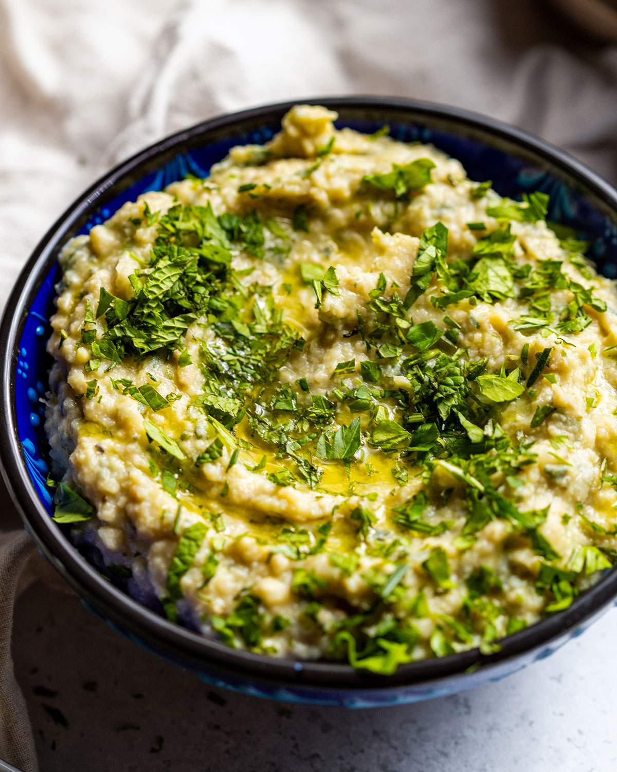 A bowl full of mashed butter beans with herbs.