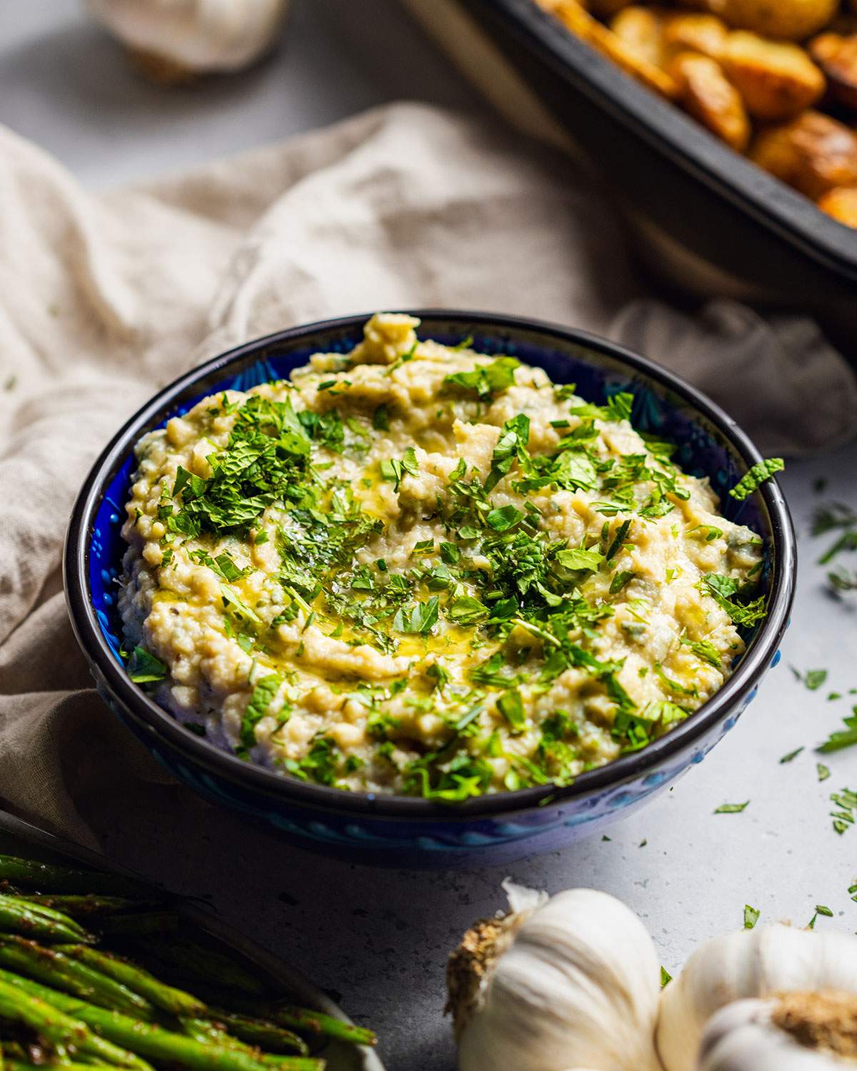 A bowl filled with herb butter bean mash with fresh herbs on top.