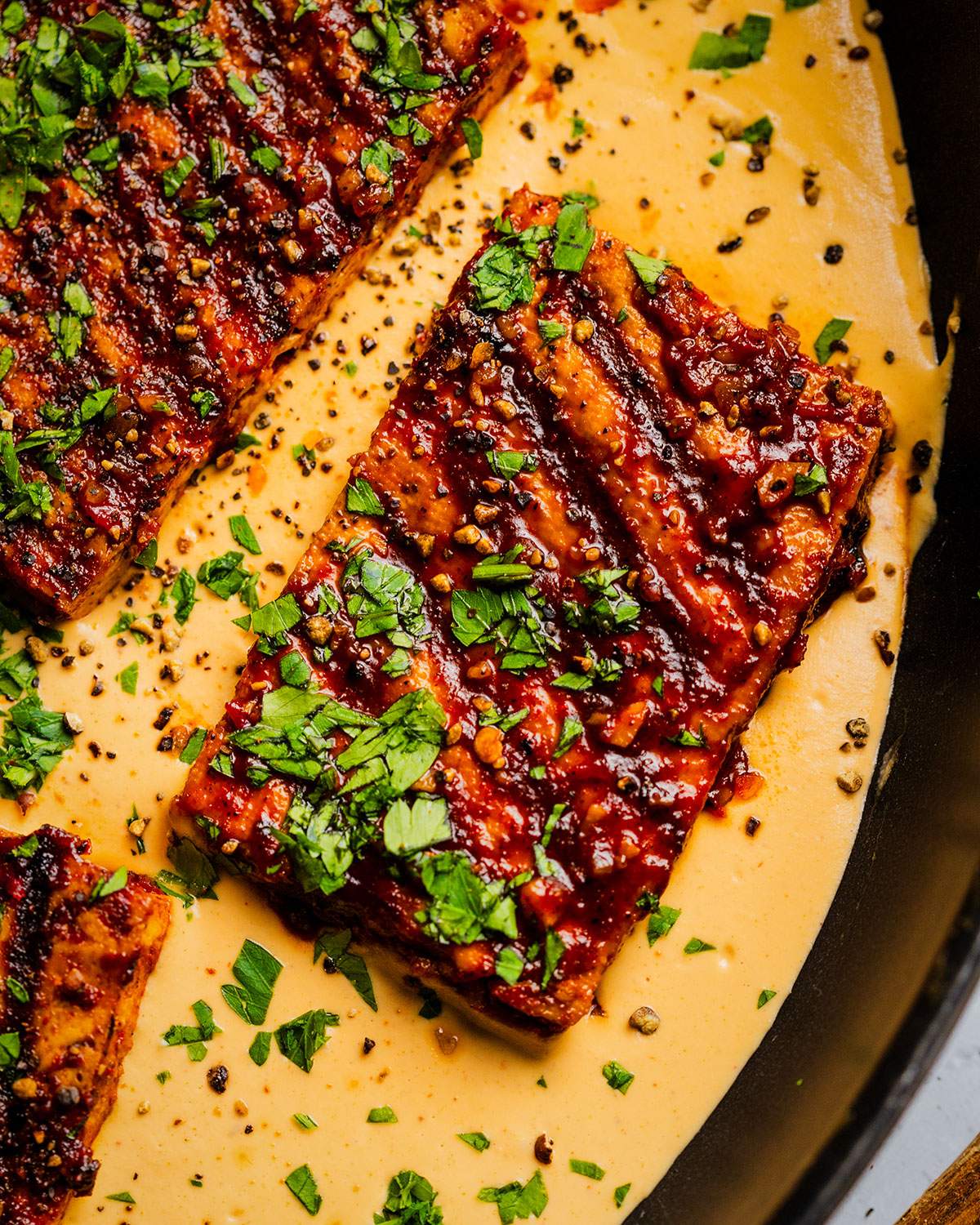 Grilled cajun tofu steaks in a skillet with cajun alfredo sauce.