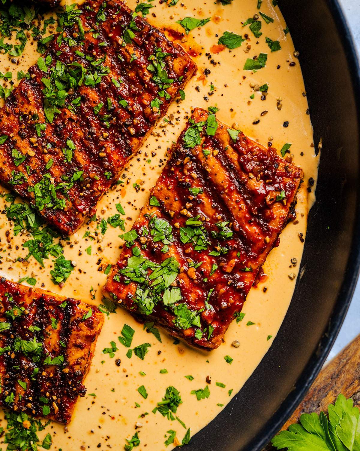 Cajun tofu steaks in a skillet with cajun alfredo sauce.