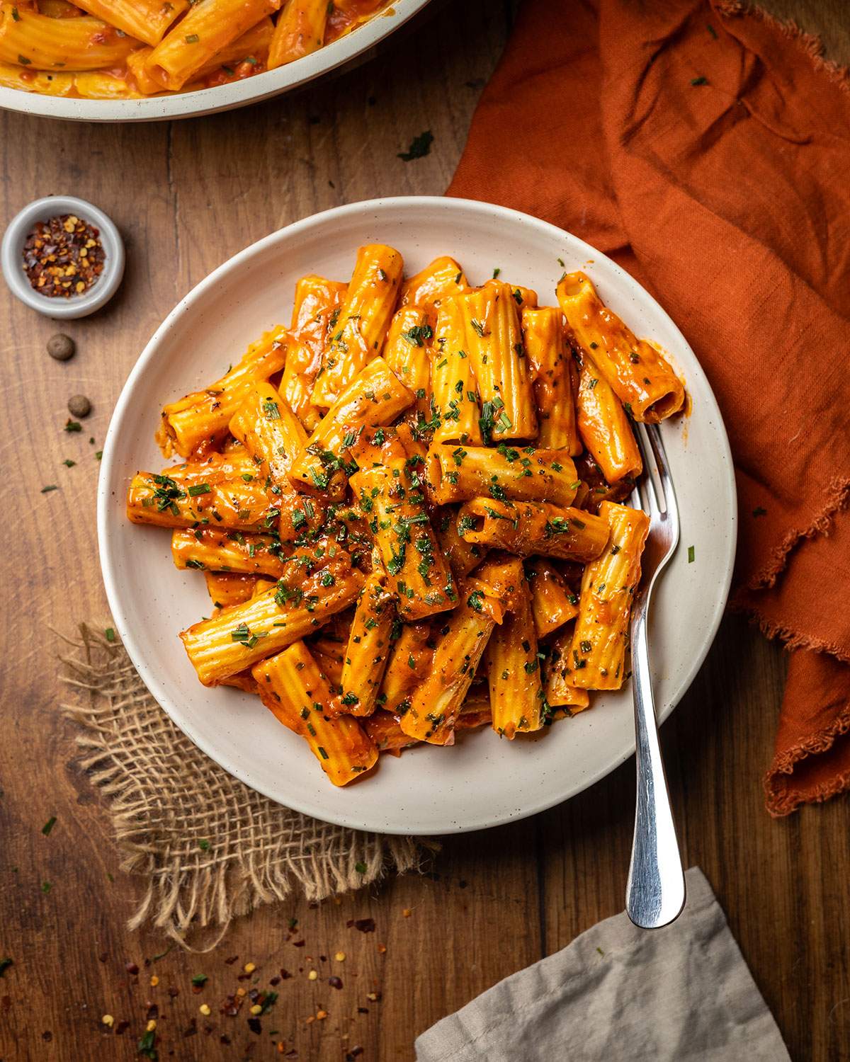 A plate filled with creamy spicy rigatoni on a wooden table ready to serve.