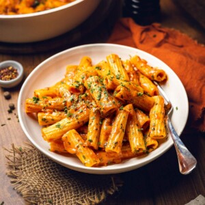 A plate filled with creamy spicy rigatoni with fresh herbs on top.