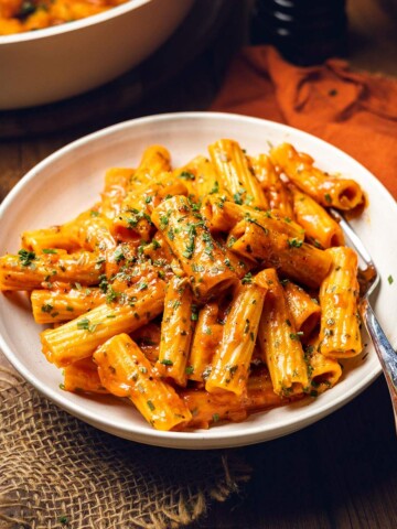 A plate filled with creamy spicy rigatoni with fresh herbs on top.