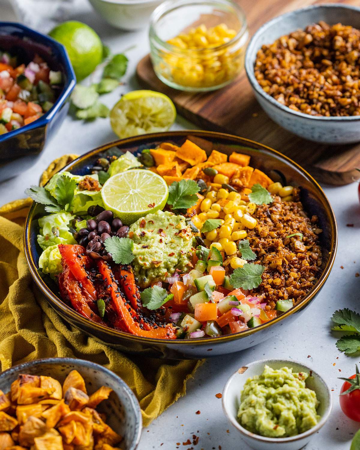 Vegan burrito bowl loaded with vegetables, walnut mince and guacamole on the dinner table.