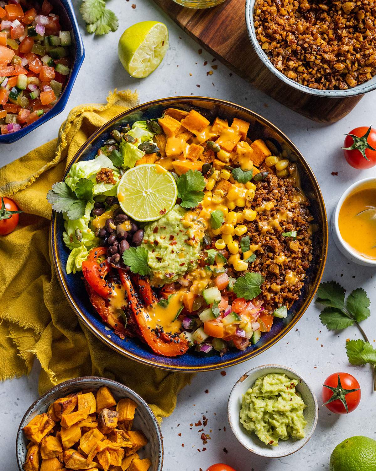 Vegan burrito bowl loaded with vegetables, walnut mince and guacamole on the dinner table.