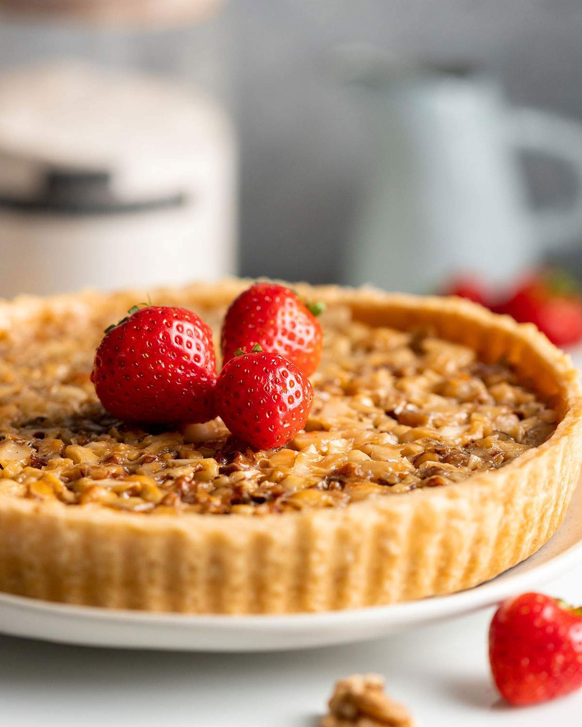 A vegan caramel tart decorated with strawberries.