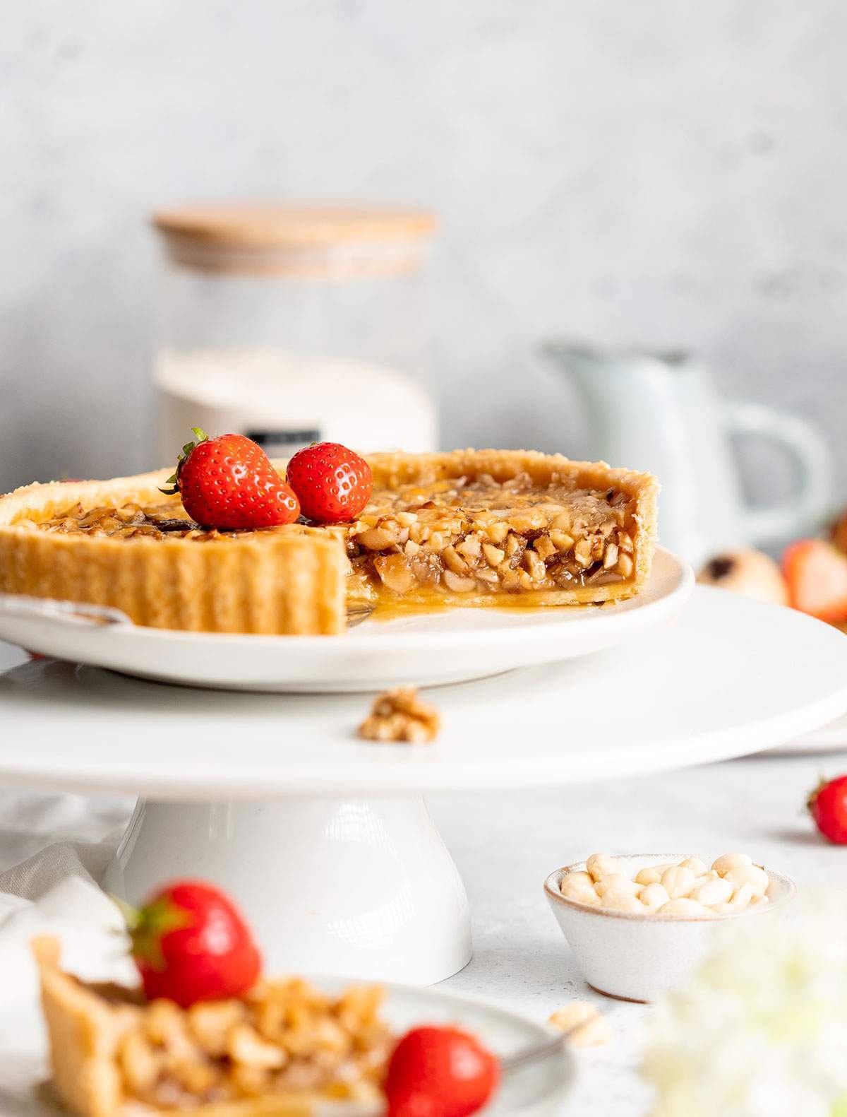 Vegan caramel tart on a cake stand with a slice cut out of it.