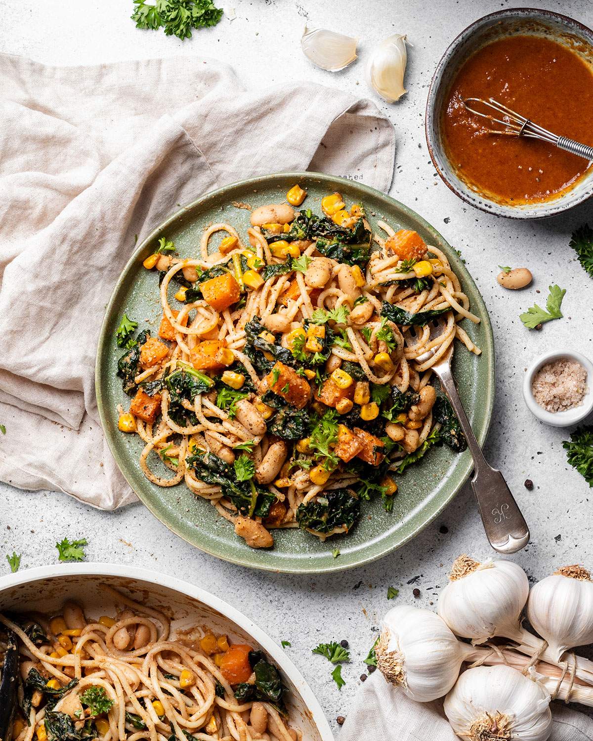 A plate filled with satay pasta next to ingredients on the table.