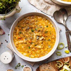White bean soup served into a bowl with fresh herbs on top.