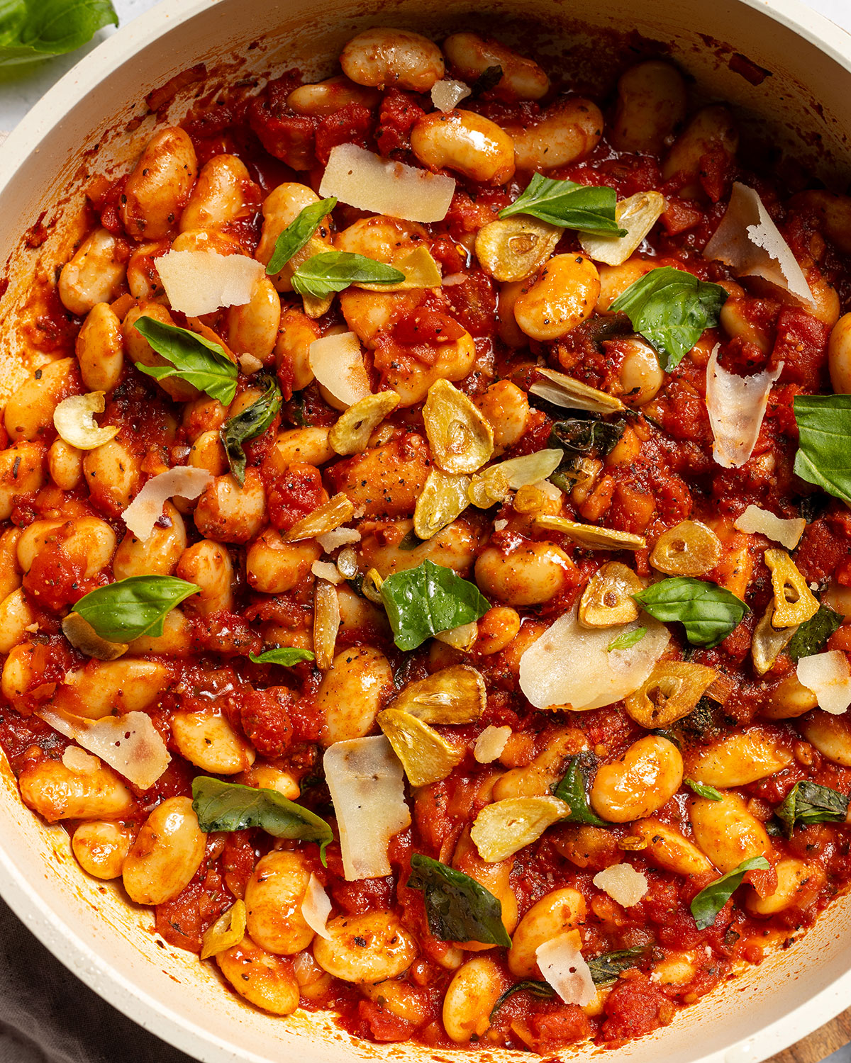 Spicy butter beans in a skillet with fresh herbs on top.