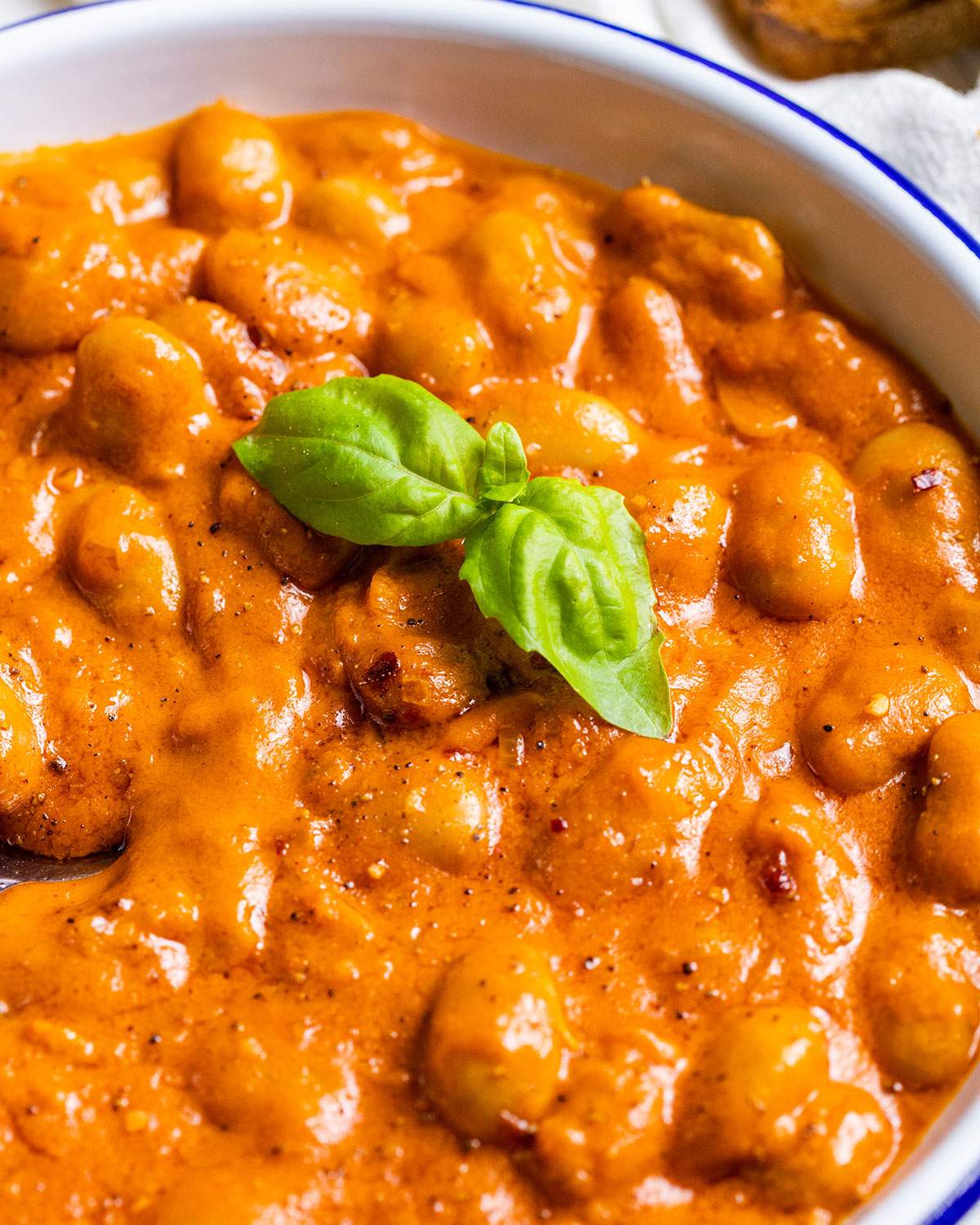 Fresh basil leaves on a plate of creamy butter beans.