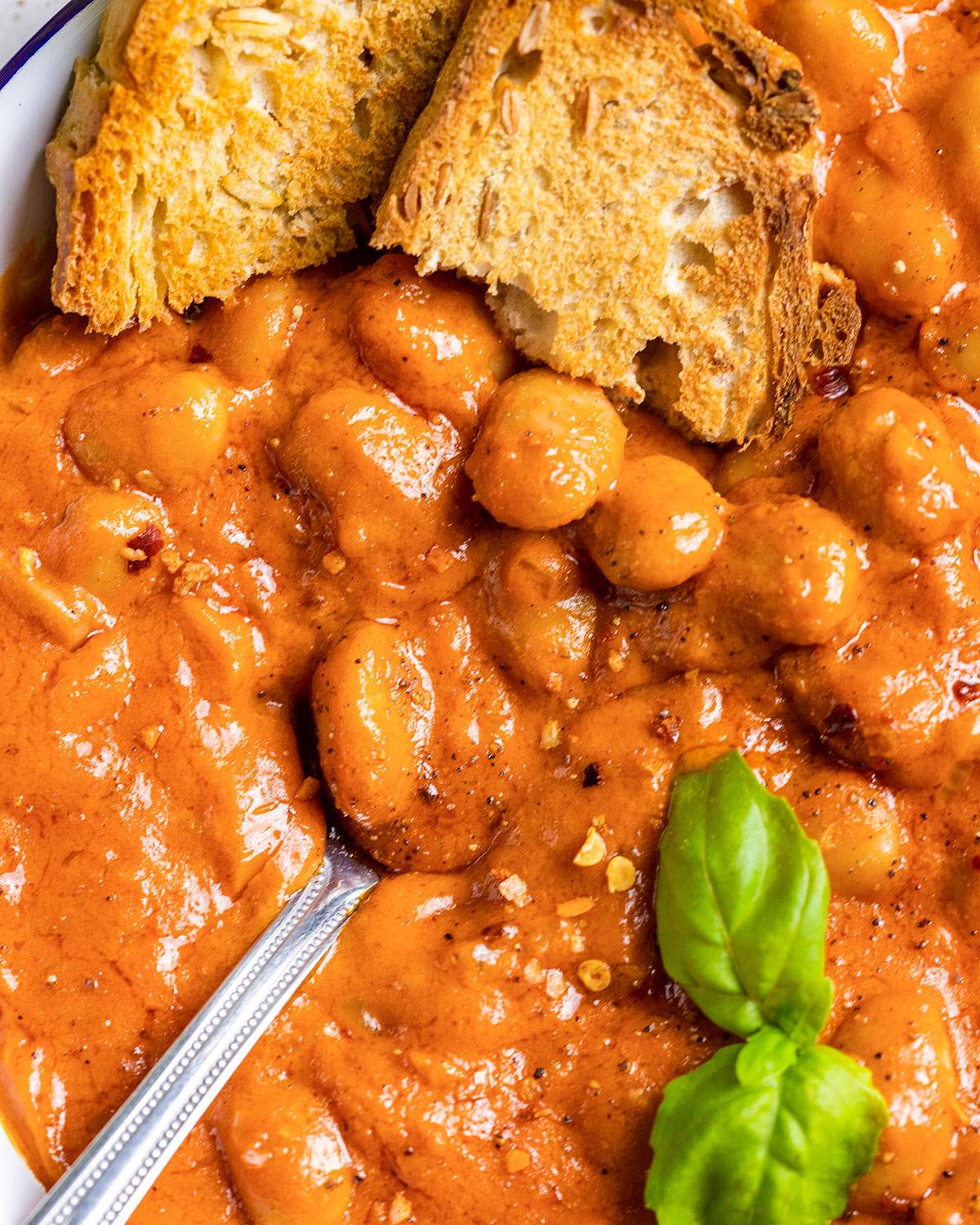 Sourdough bread on the edge of a bowl of creamy butter beans alla vodka.