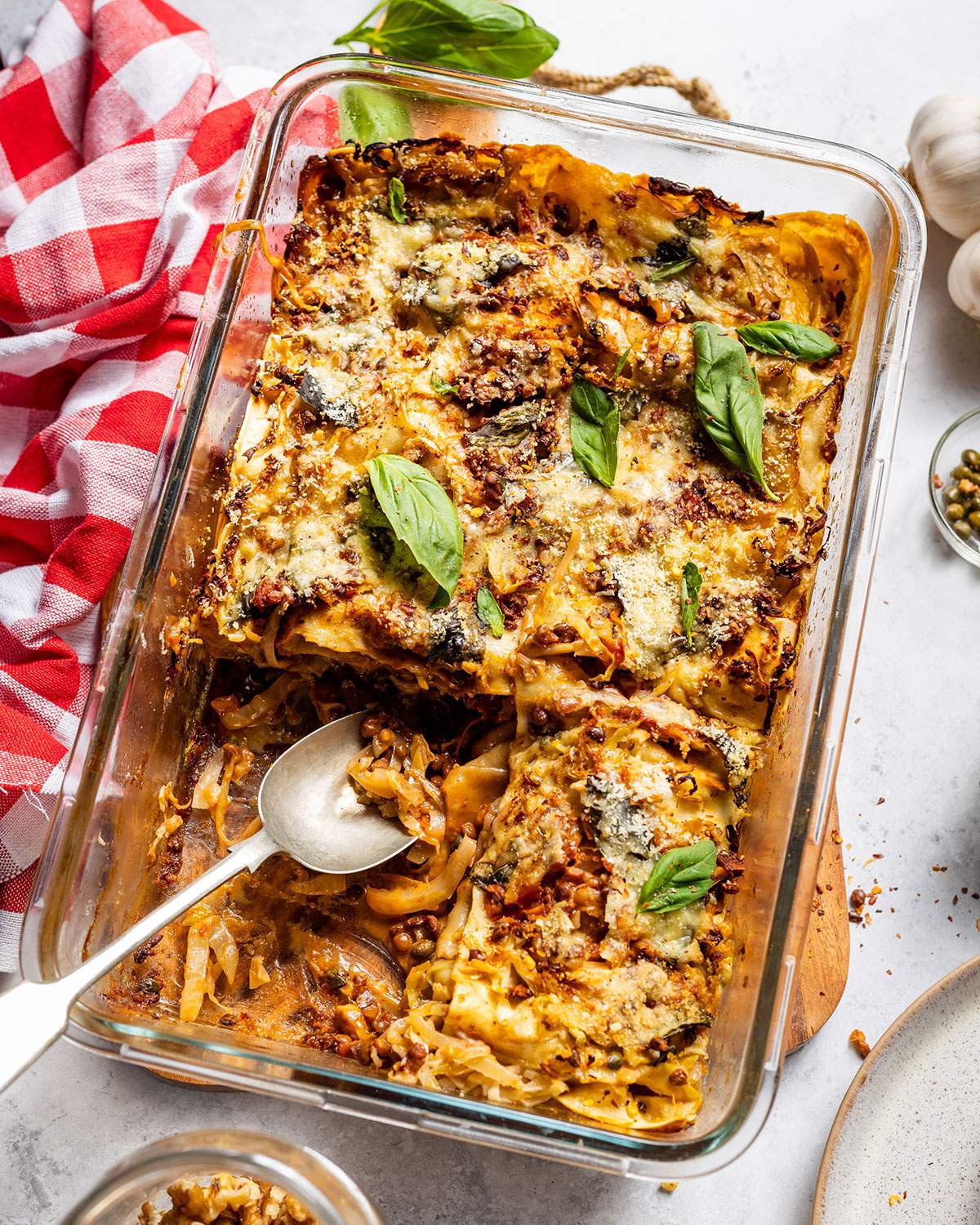 Baked cabbage and walnut lasagna with a serving spoon.