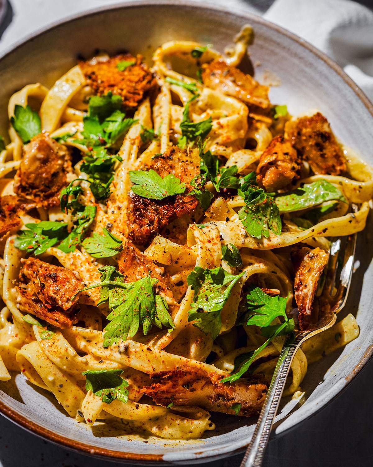 Creamy cajun alfredo with vegan cajun chicken pieces in a pasta bowl.