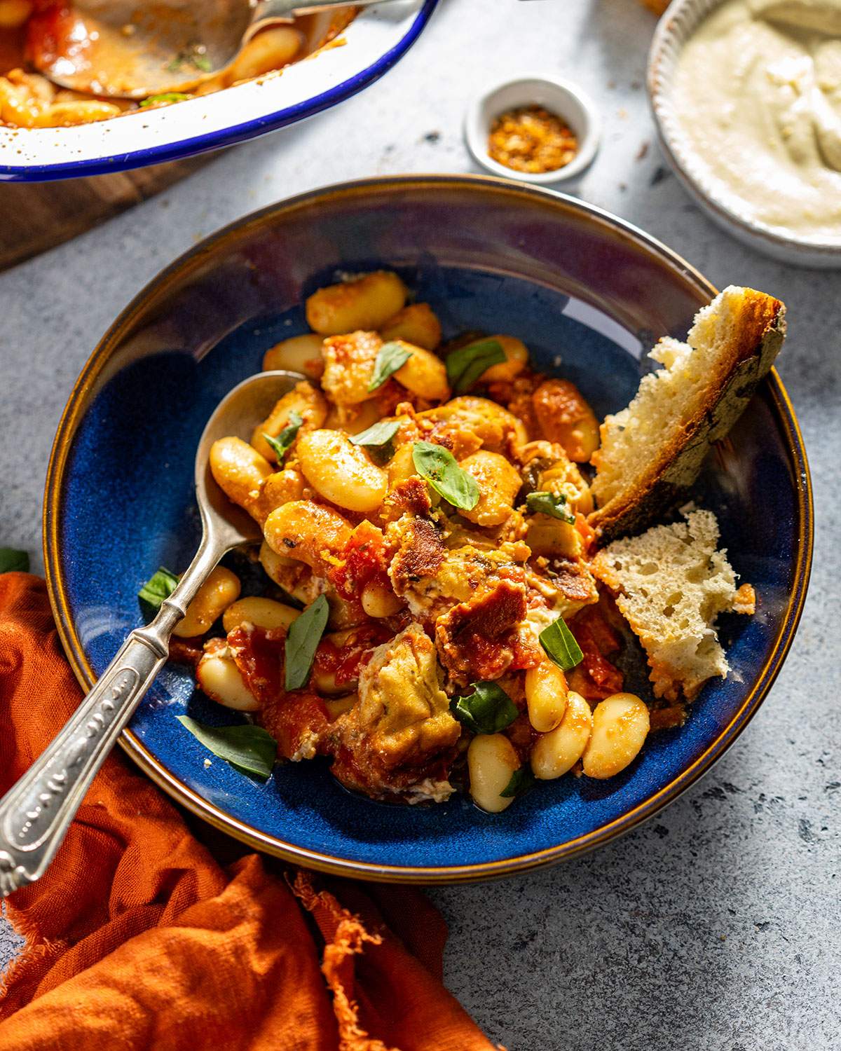 Baked caprese butter beans served in a bowl with crusty bread on the side.
